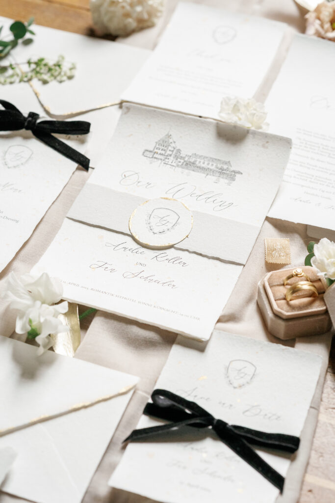 Luxuriöse Hochzeitspapeterie auf handgeschöpftem Papier mit handgemalter Illustration, Hochzeitswappen und schwarzer Samtschleife